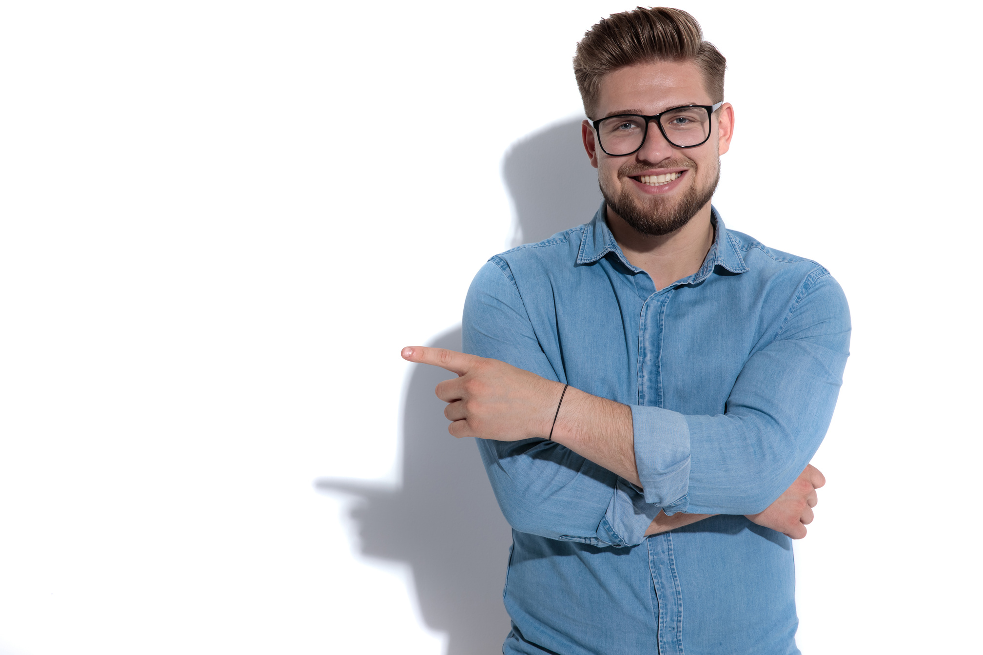 smiling young casual man pointing finger to side